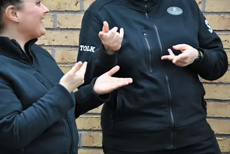 Två tolkar använder teckenspråk.