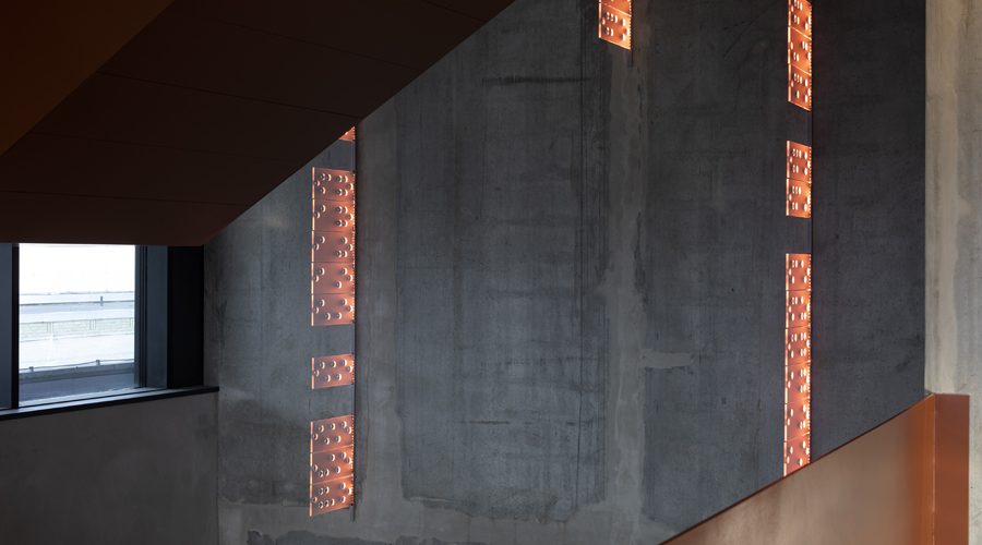 ljuspaneler i orange som sitter på en betongvägg inomhus