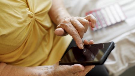 En person sitter med en mobiltelefon i handen