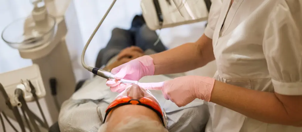 En tandläkare behandlar en patient som ligger på en behandlingsstol.