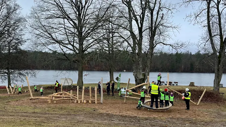 Barn i reflexvästar leker på naturlekplats i vattenbrynet