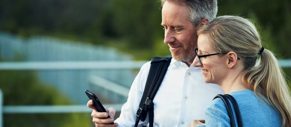 En man och en kvinna tittar på en mobil.