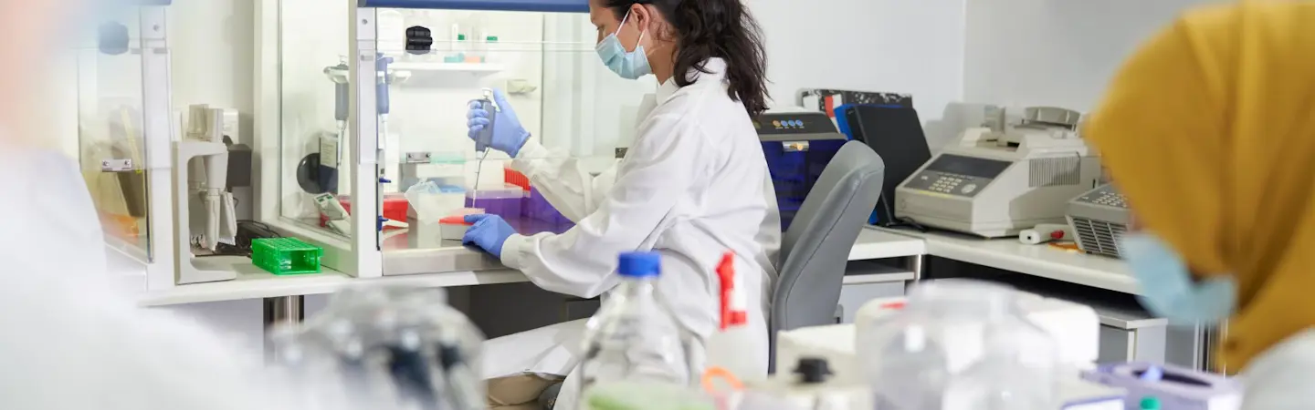 Kvinna i labbkläder arbetar i ett laboratorium.
