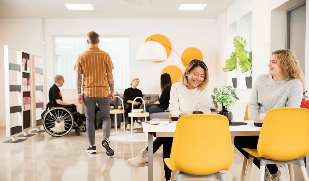 Vuxna studenter i en färgglad campusmiljö.