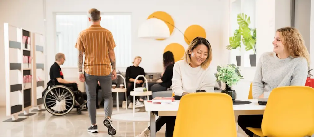 Vuxna studenter i en färgglad campusmiljö.