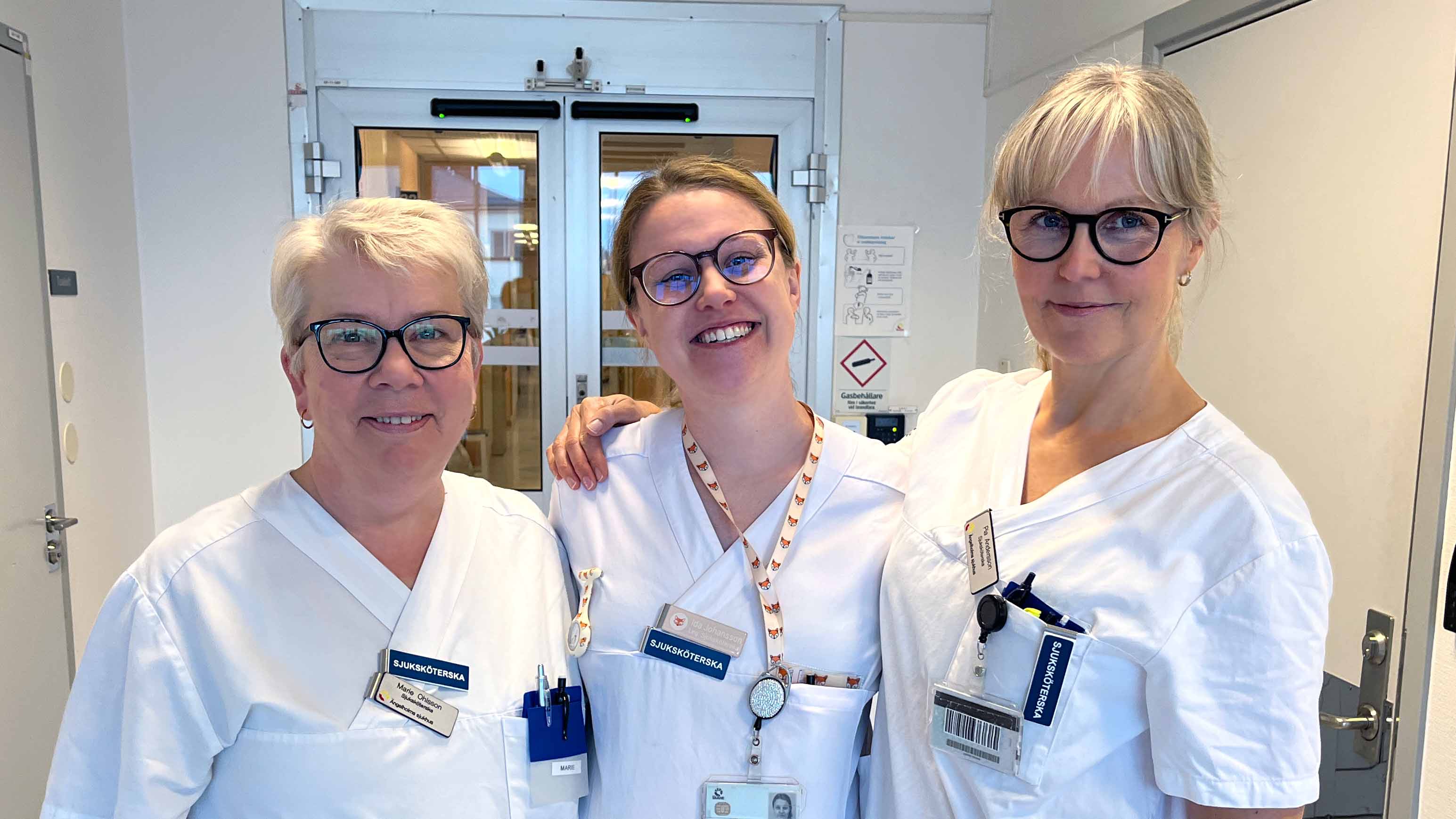 Marie Ohlsson, sjuksköterska på Njurmottagningen Ängelholm, och Ida Johansson och Pia Andersson, sjuksköterskor på Dialysmottagningen Ängelholm, iklädda vita vårdkläder, står i en sjukhuskorridor, tittar in i kameran och ler.