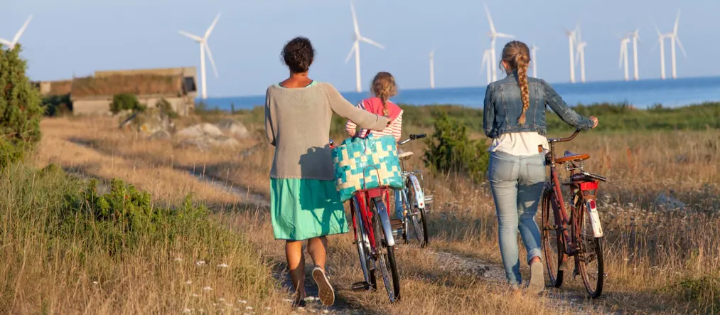 Vindkraftverk i bakgrunden, cyklister i framgrunden.